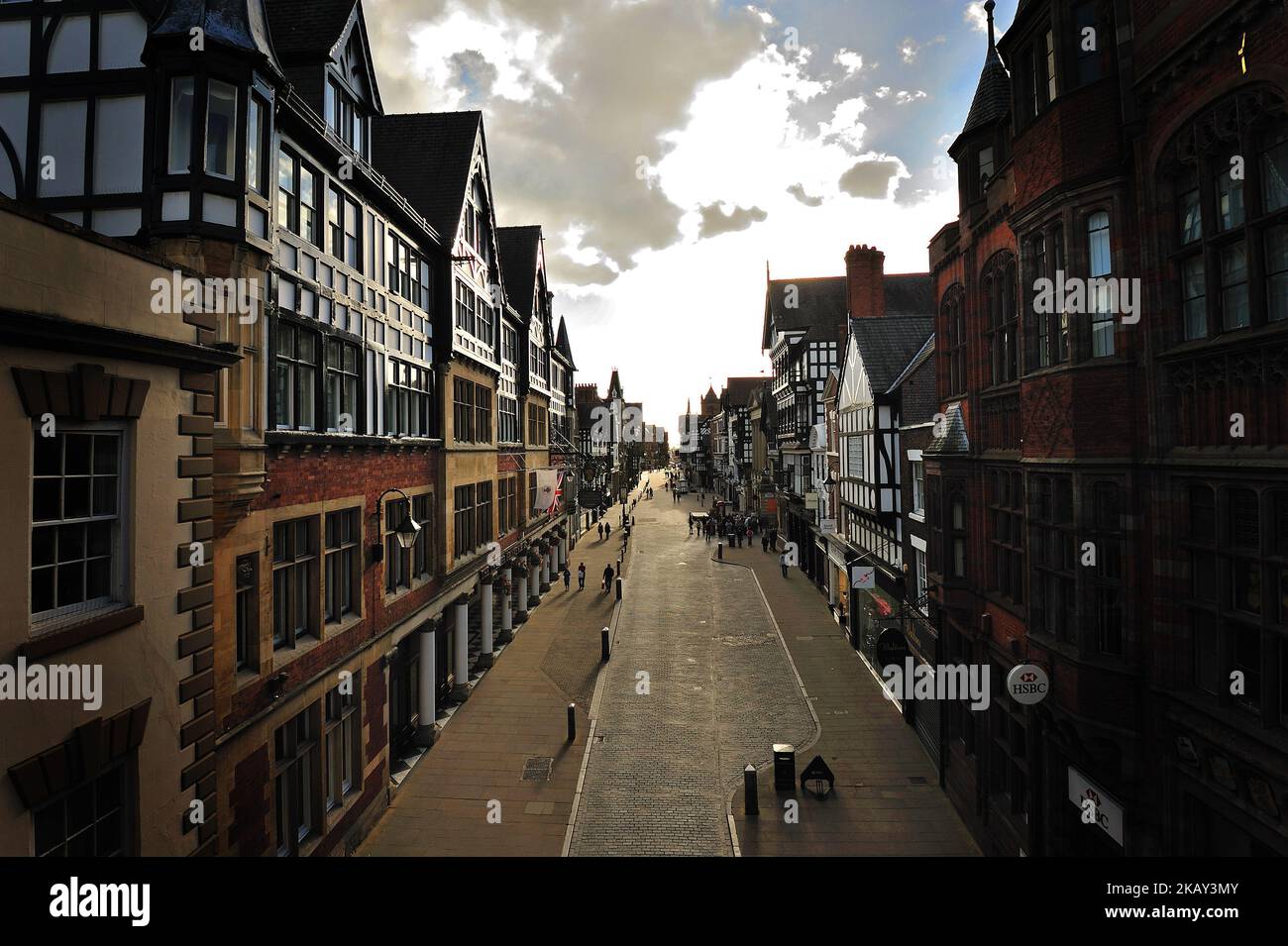 A paved road amid old dense buildings at sunset in the beautiful historic city of Chester, England Stock Photo
