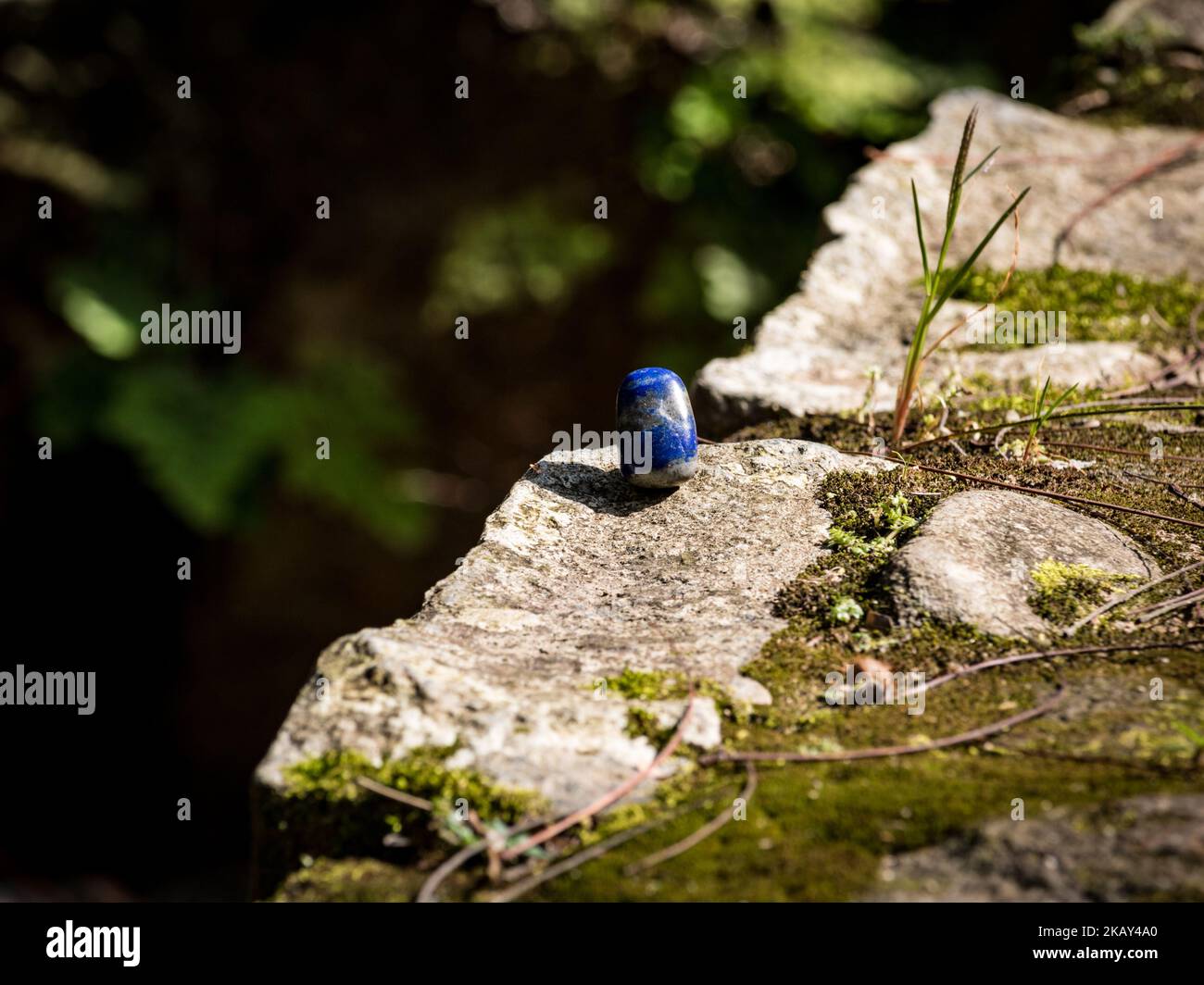 A closeup shot of a lapis lazuli blue crystal on a mossy rock surface Stock Photo