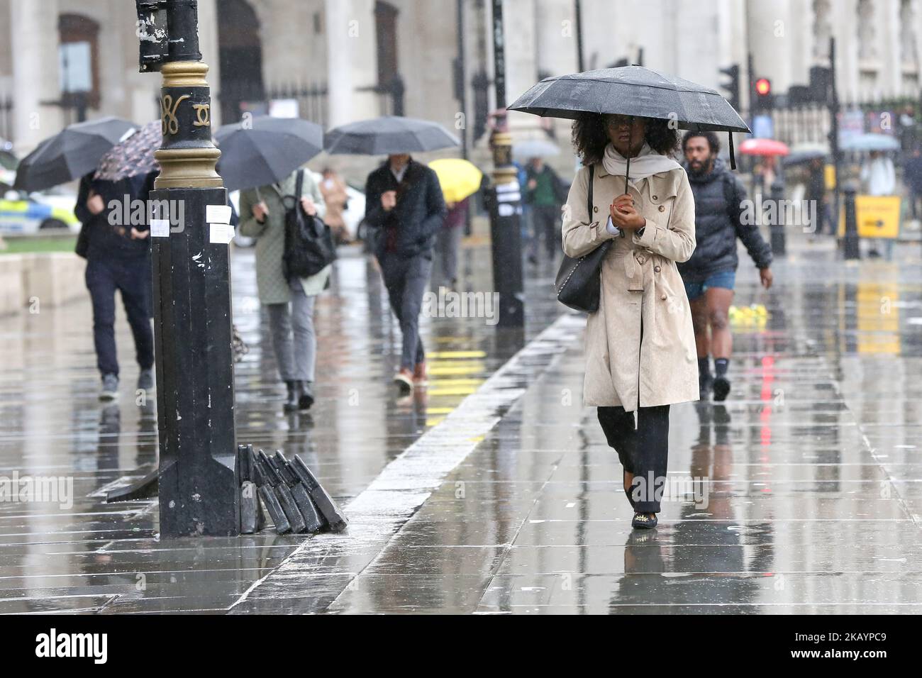 People shelter under umbrellas during rainfall in London. According to ...