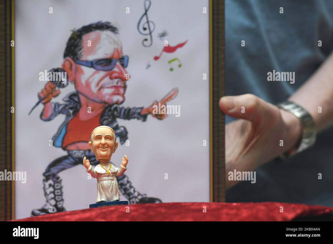 A mini size Pope Francis Bobble head in front of a watercolor caricature which features the Irish singer-songwriter Bono, made by an Irish Artist Ray Sherlock, on display at Dublin's Balla Ban Art Gallery. The gallery owner Frank O'Dea will be giving them out for free with every purchase made during the Pope's visit to Ireland. Pope Francis is due to visit Ireland from August 21 to 26 in what will be the first papal visit since Pope John Paul II came in 1979. On Wednesday, July 18 2018, in Dublin, Ireland. (Photo by Artur Widak/NurPhoto)  Stock Photo