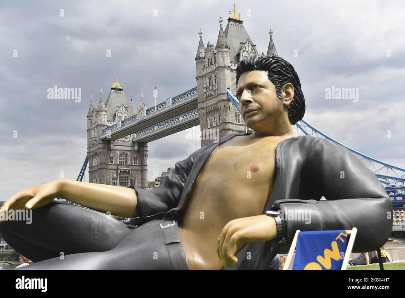 A giant statue of US actor Jeff Goldblum has been erected next to the Tower Bridge, London on July 18, 2018. The monument 7.6m (25ft) depicts the Jurassic Park star reclining, open-shirted, in a recreation of his famous pose from the 1993 dinosaur blockbuster. (Photo by Alberto Pezzali/NurPhoto) Stock Photo
