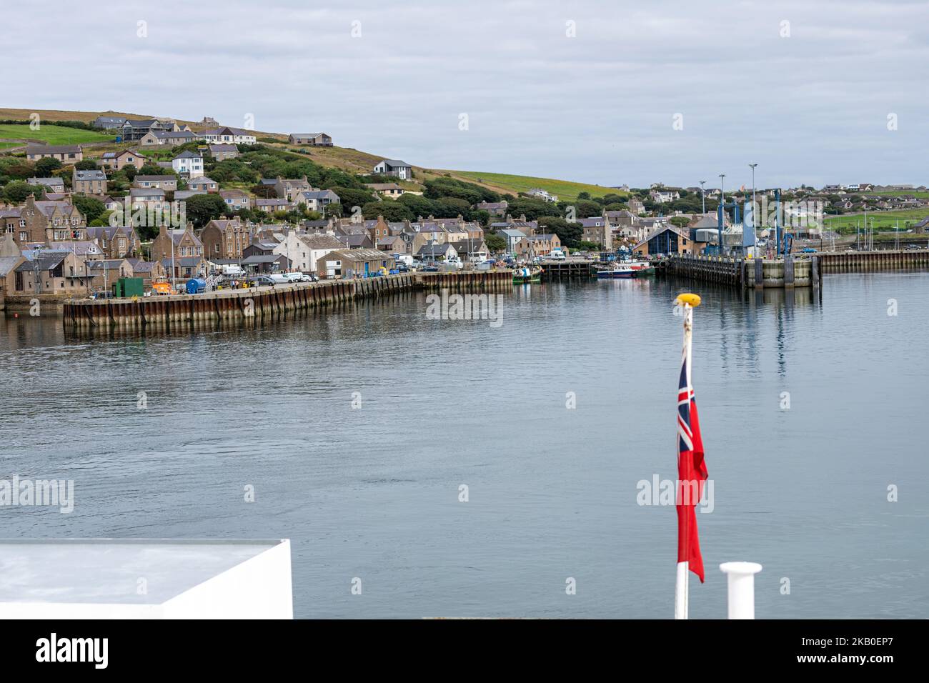 View of Stromness from the NorthLink Ferries and Red Ensign Flag (the UK Merchant Navy’s official flag), Orkney, Scotland, UK Stock Photo