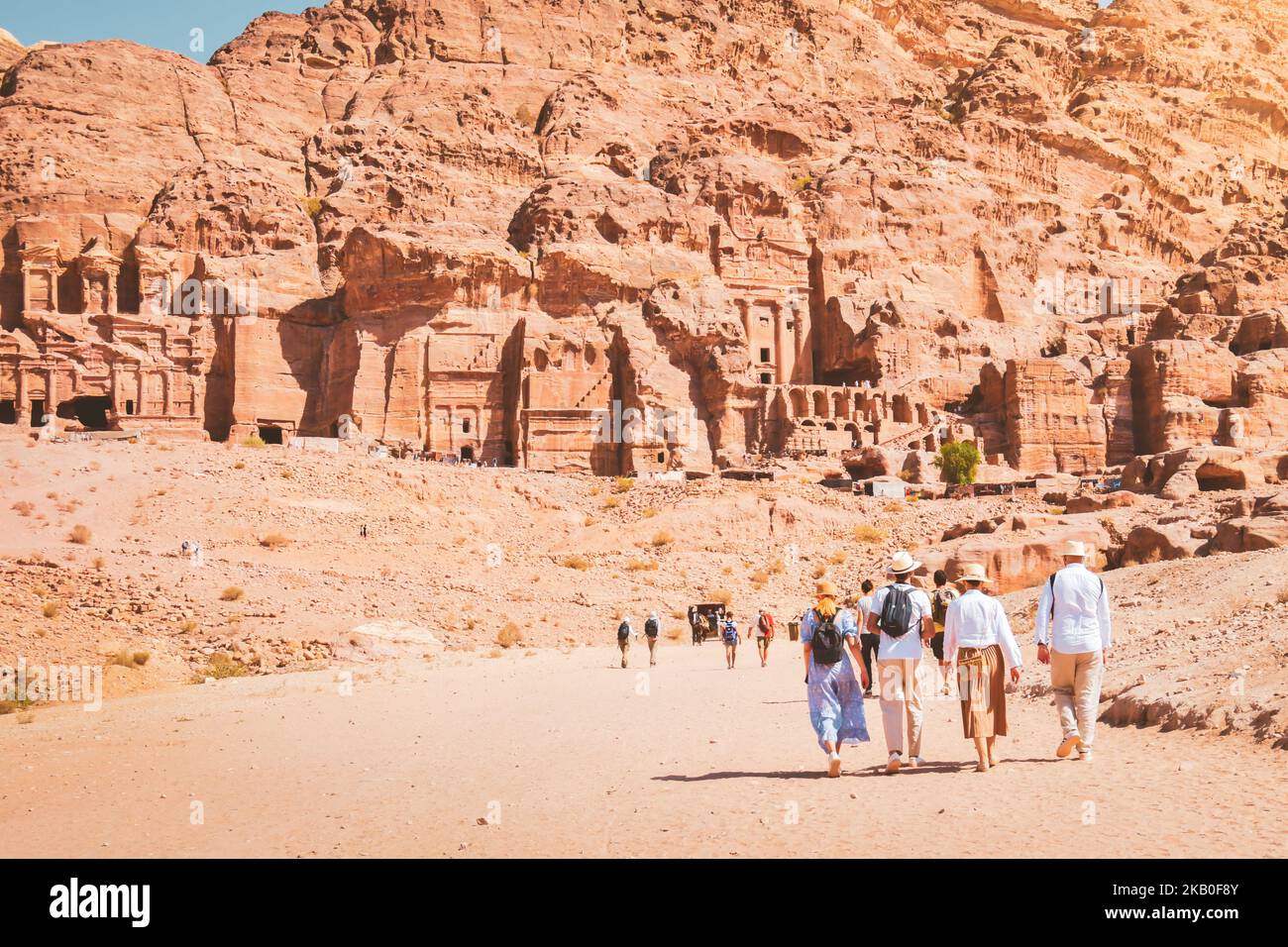 Group of friends couple tourist walk by caves of tombs in ancient city of Petra, Jordan. It is know as the Loculi. Petra has led to its designation as Stock Photo