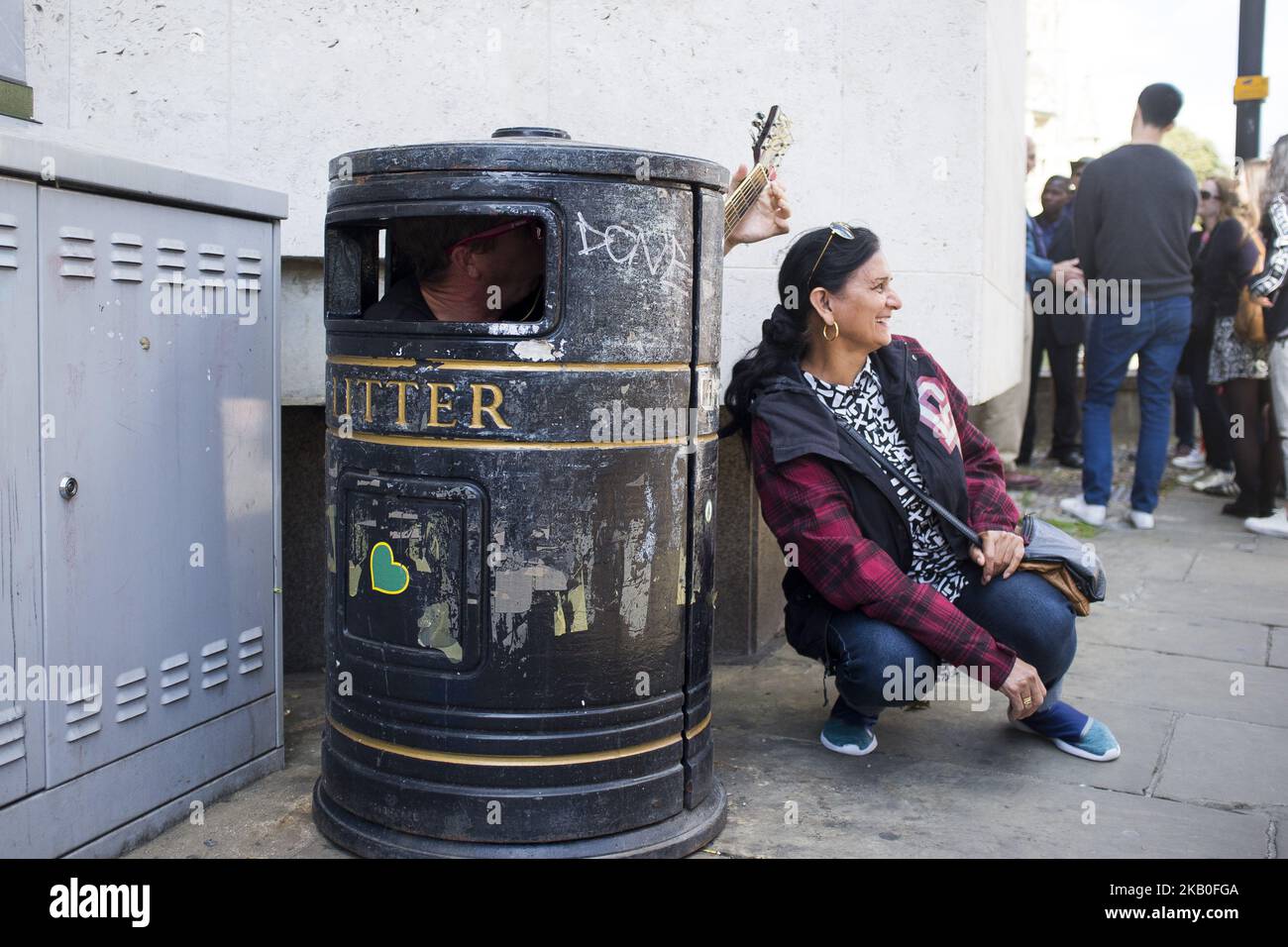 A busker is pictured as he plays guitar into a garbage bin in Cambridge ...