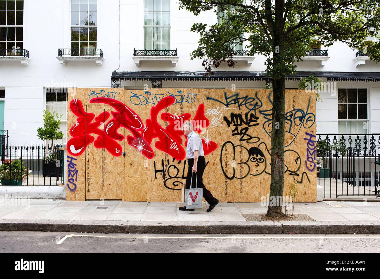 A man walks past a boarded-up home as revellers and paraders pack the streets of Notting Hill in west London for the main day of the 2018 Notting Hill Carnival in London, England, on August 27, 2018. Hundreds of thousands are expected to attend, with the Metropolitan Police meanwhile out in force in their annual bid to counter the carnival's reputation as a hotspot for criminality and gang violence. (Photo by David Cliff/NurPhoto) Stock Photo