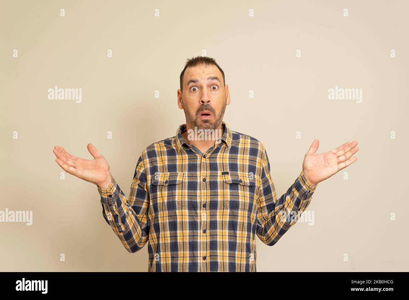 Wow. Attractive male half-length front portrait on beige studio backgroud. Emotional surprised bearded man standing with open mouth. Human emotions Stock Photo