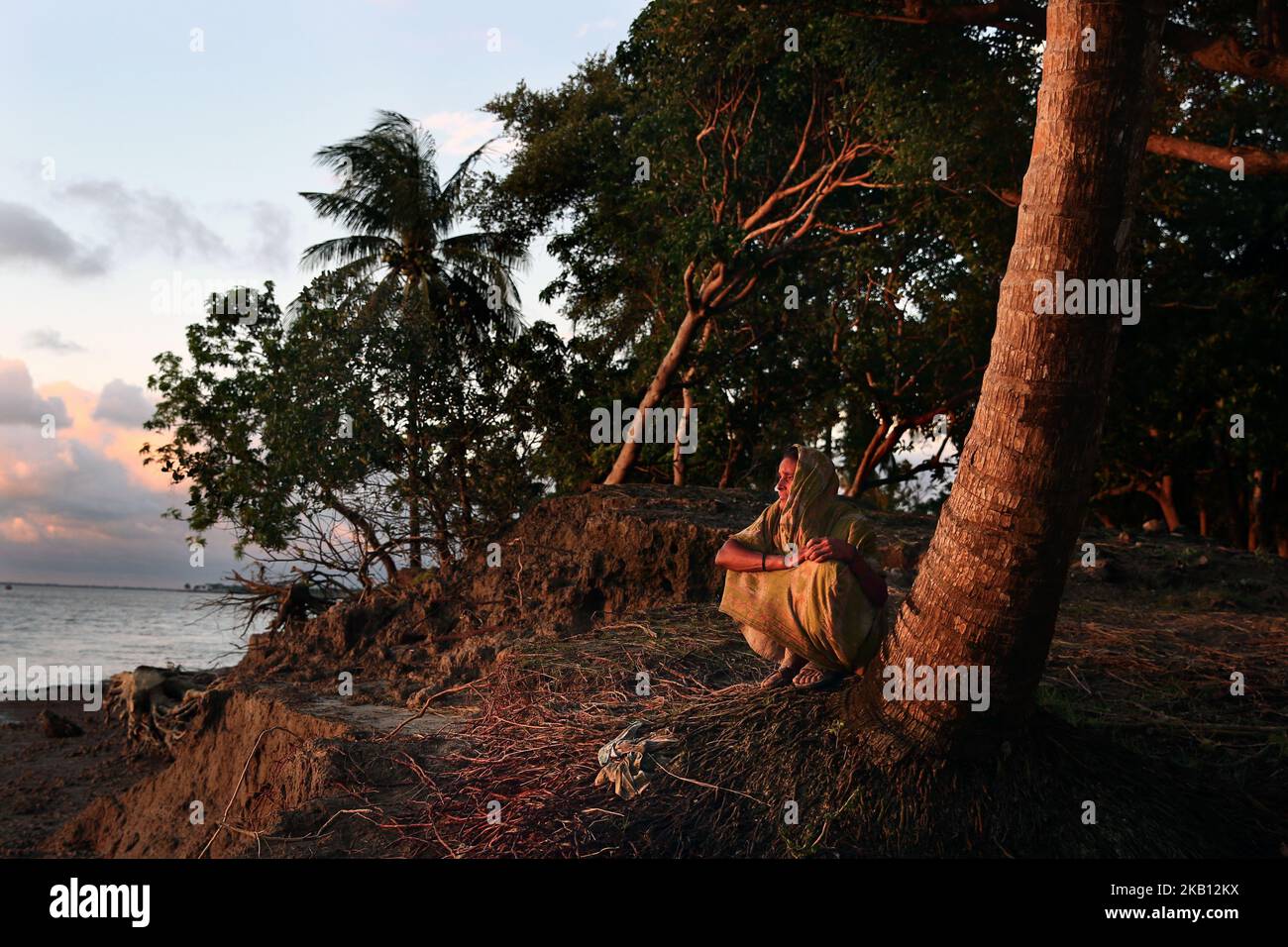 Tulu rani (85) sits near the bank of the river where she has lost her land to river erosion in Monpura Island, Bhola, Bangladesh, on September 5, 2018. The Bhola is a southern part district of Bangladesh, a country which is ranked as one of the worlds most vulnerable countries to climate change. The southern part of Bangladesh is known to be especially vulnerable. The Bhola district is no exception. Situated where freshwater from the rivers meets saltwater from the Bay of Bengal, the district is exposed both to the activity of two rivers, as well as to tidal changes and cyclones from the ocean Stock Photo