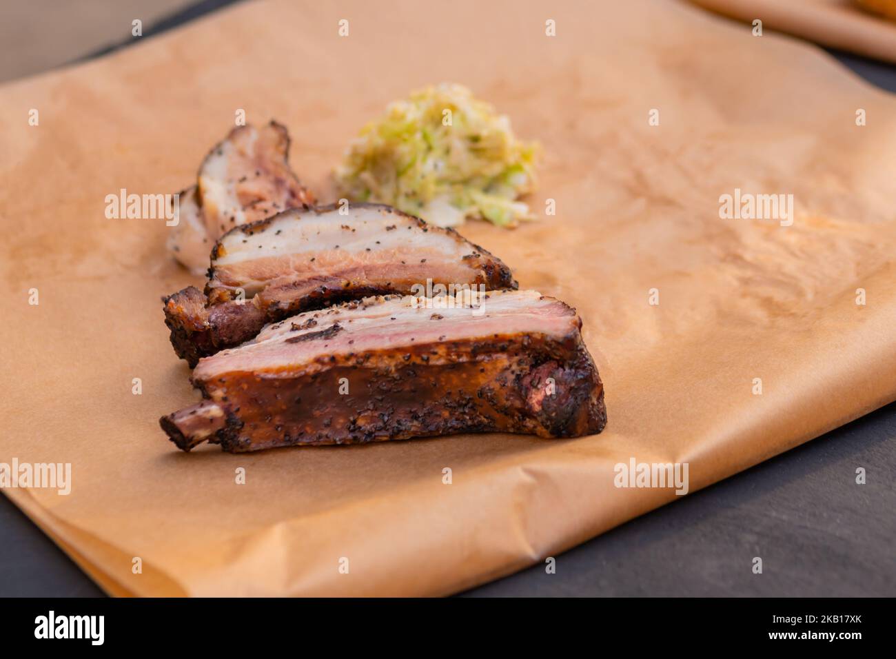 Slices of beef ribs on craft paper on table at summer local food festival. Stock Photo