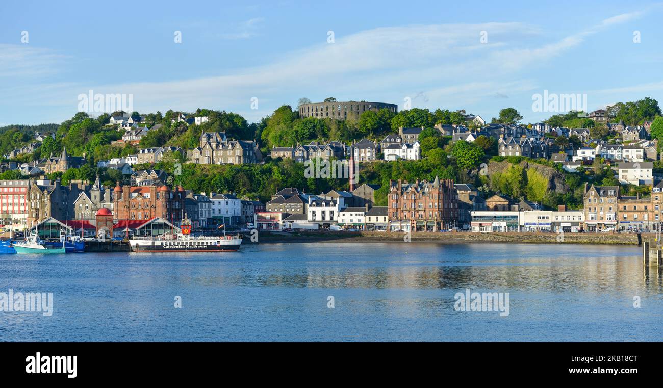 Oban Harbour from the Oban to Mull Ferry with CalMac Ferry and McCaig's Tower  taken early summer evening Stock Photo