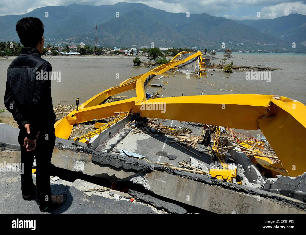 Palu residents stand near on the Palu Bridge, which collapsed in the recent earthquake and tsunami, near Talise Beach in Palu, Central Sulawesi, Indonesia, 02 October 2018. According to reports, at least 844 people have died as a result of a series of powerful earthquakes that hit central Sulawesi on 28 September 2018 that triggered a tsunami. (Photo by Dasril Roszandi/NurPhoto) Stock Photo