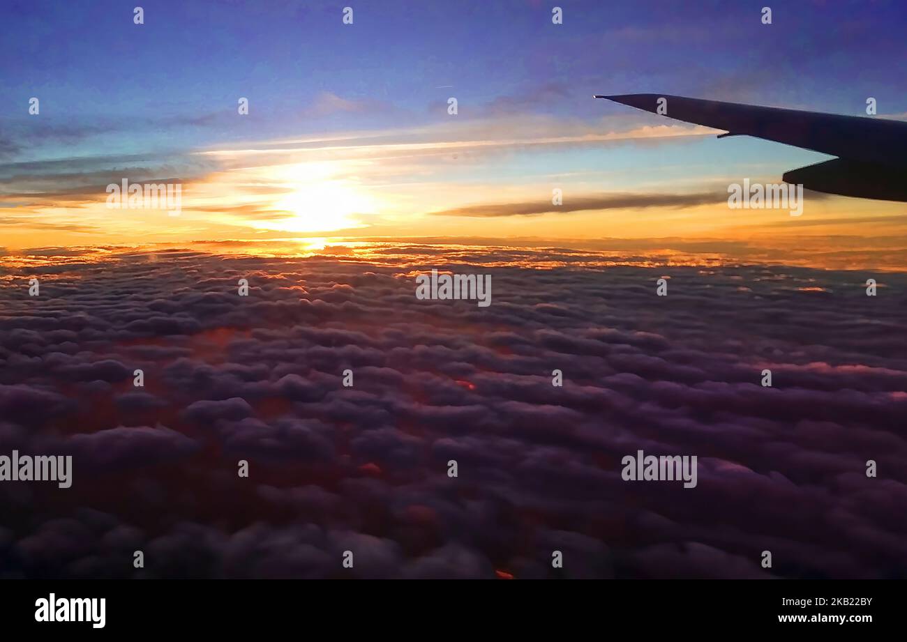 Sunset above the clouds with airplane wing Stock Photo