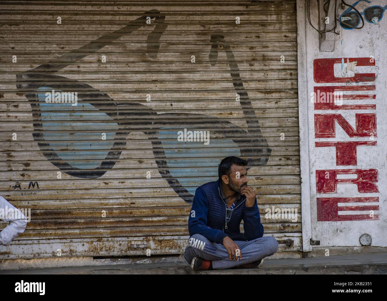 A man rests on the porch of a shuttered shop during a strike against the killing of a Kashmiri rebel commander on October 12, 2018 in Srinagar, the summer capital of Indian administered Kashmir, India. Kashmiri youth clashed with Indian government forces who were deployed in strength in different parts of Srinagar on Friday to prevent protests against the killing of a Kashmiri rebel commander in Kupwara district of Indian-administered Kashmir the previous day. Manan Wani, who had quit his doctorate in Geology at an Indian university to join the Hizb-ul-Mujahideen militant outfit this year and  Stock Photo