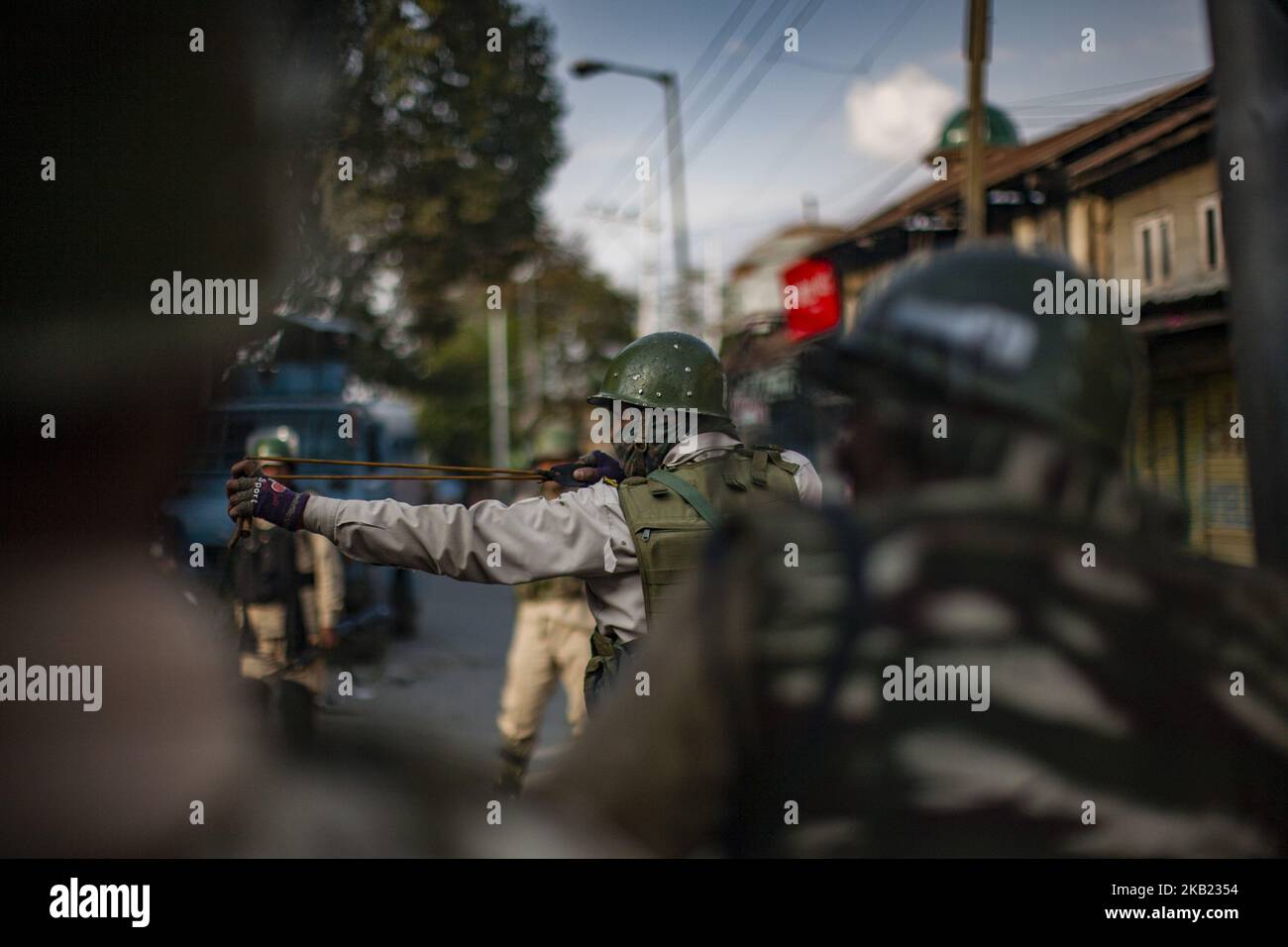 An Indian paramilitary trooper shoots stones with his catapult at Kashmiri Muslim protesters during a protest against the killing of a Kashmiri rebel commander on October 12, 2018 in Srinagar, the summer capital of Indian administered Kashmir, India.Kashmiri youth clashed with Indian government forces who were deployed in strength in different parts of Srinagar on Friday to prevent protests against the killing of a Kashmiri rebel commander in Kupwara district of Indian-administered Kashmir the previous day. Manan Wani, who had quit his doctorate in Geology at an Indian university to join the H Stock Photo