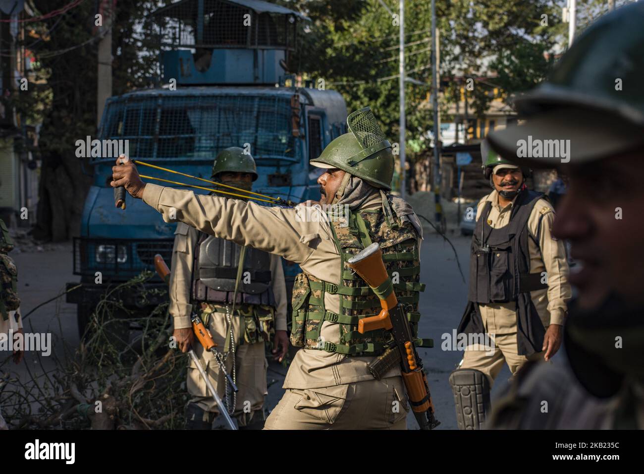 An Indian paramilitary trooper shoots stones with his catapult at Kashmiri Muslim protesters during a protest against the killing of a Kashmiri rebel commander on October 12, 2018 in Srinagar, the summer capital of Indian administered Kashmir, India.Kashmiri youth clashed with Indian government forces who were deployed in strength in different parts of Srinagar on Friday to prevent protests against the killing of a Kashmiri rebel commander in Kupwara district of Indian-administered Kashmir the previous day. Manan Wani, who had quit his doctorate in Geology at an Indian university to join the H Stock Photo
