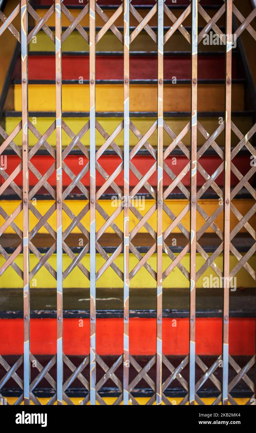 Painted stairs and a metal accordion security gate make a geometric pattern Stock Photo