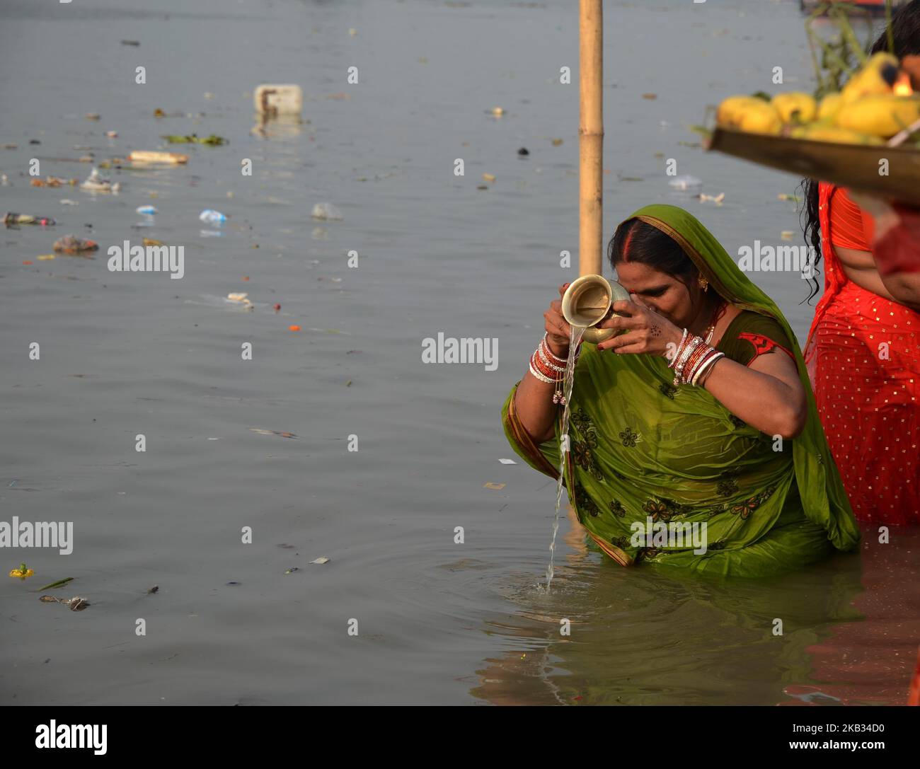 Indian Hindu woman devotee offering prayers to the Sun God on the banks