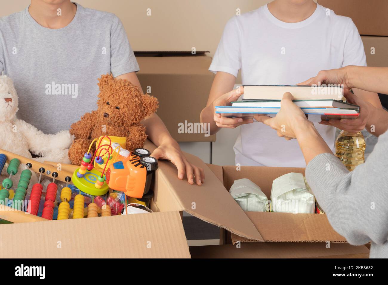 Young volunteers collect donations for charity indoors. Donation boxes with clothes, food, toys