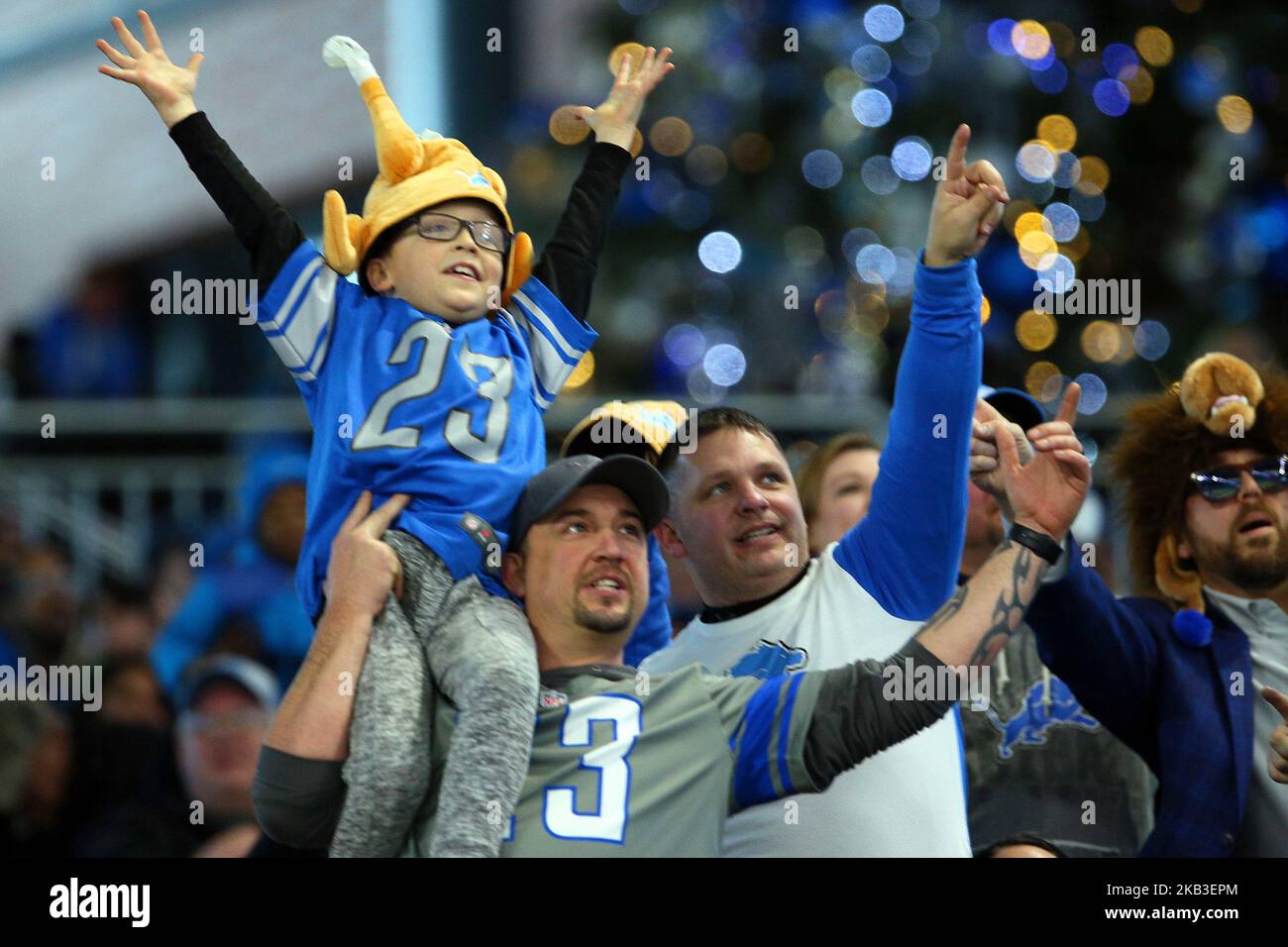 A fan lifts up a young fan dressed in a turkey hat during the first half of an NFL football game