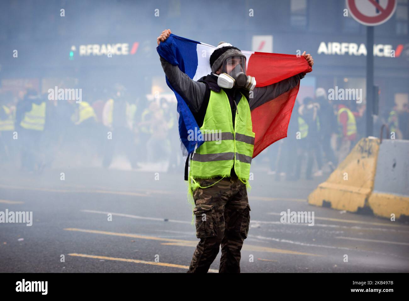 A Yellow Vest wrapped in a French Flag confronts riot police and water ...