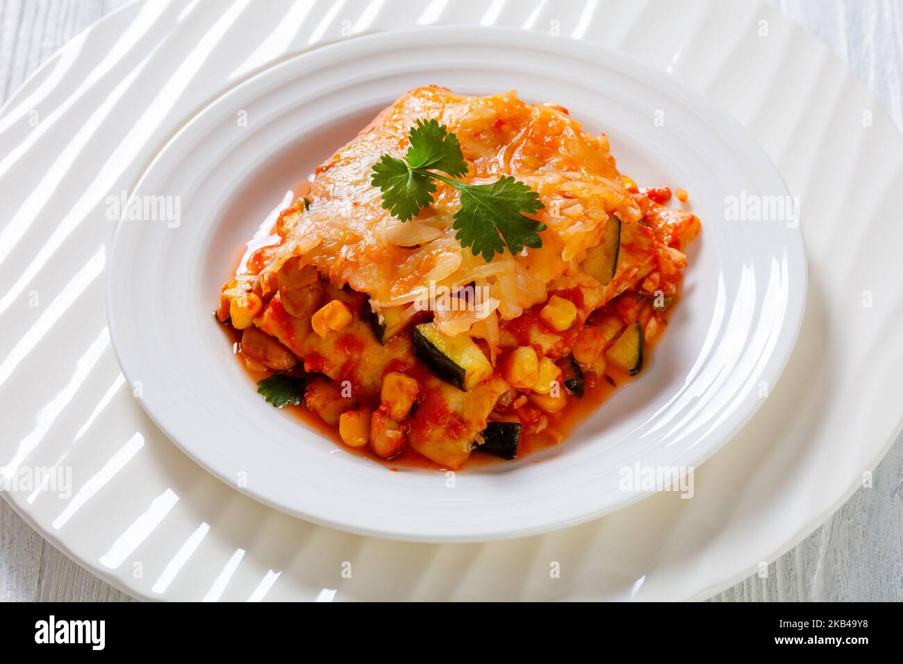 enchilada casserole layered with tortillas, sauce, pinto beans, corn