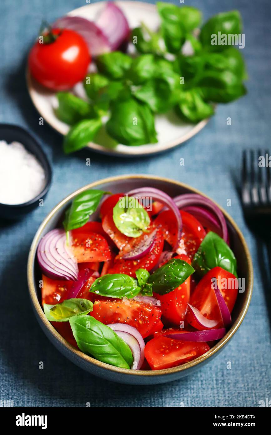 Bright healthy salad with tomatoes, basil and blue onions. Stock Photo