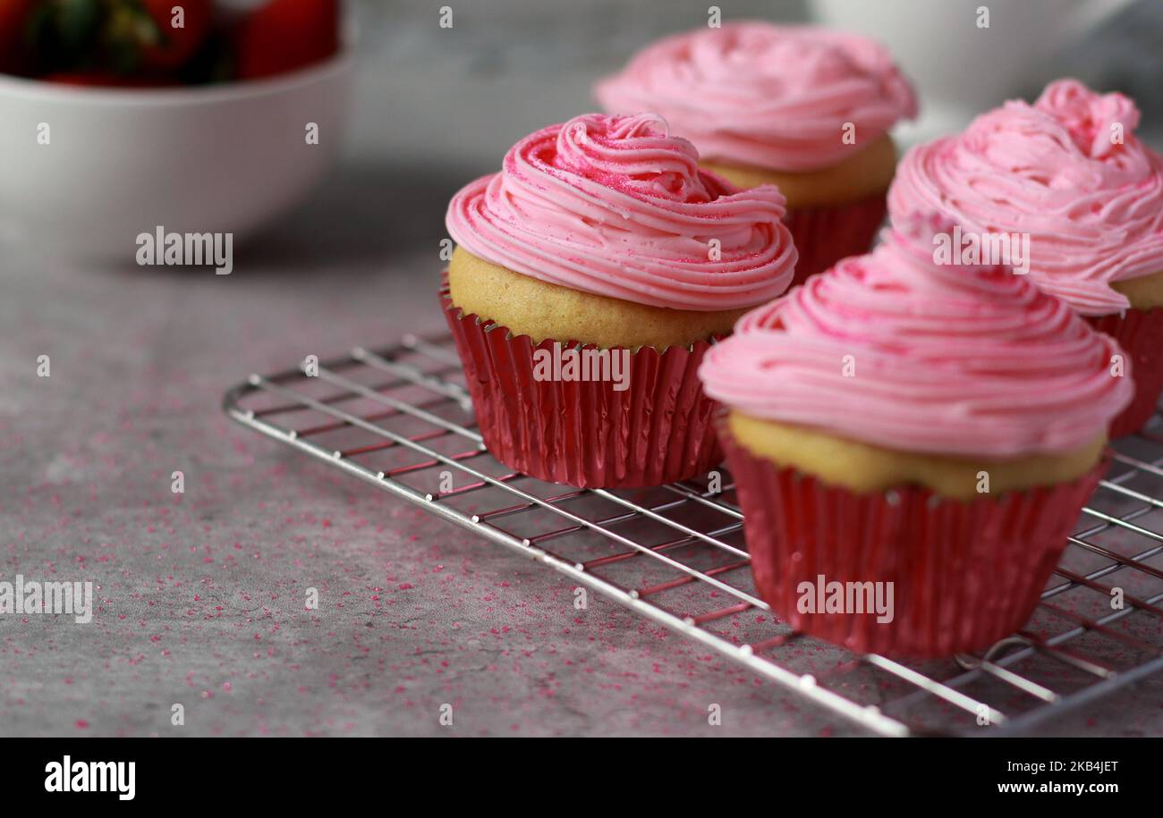 close up of vanilla muffins decorated with pink buttercream frosting on top Stock Photo