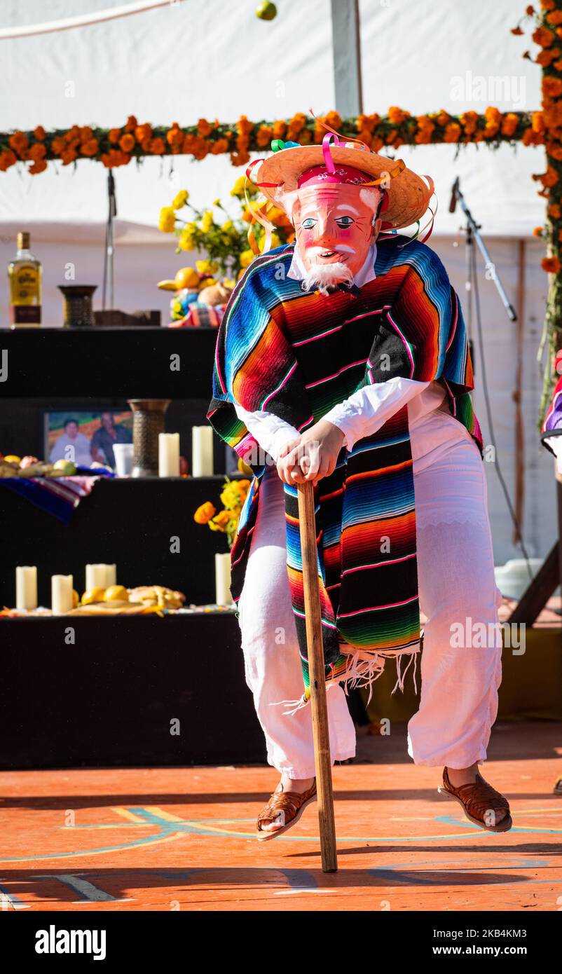 A costumed dancer hops off the ground as part of the humorous Viejitos Dance (Dance of the Old Men), performed during a Dia de los Muertos event. Stock Photo