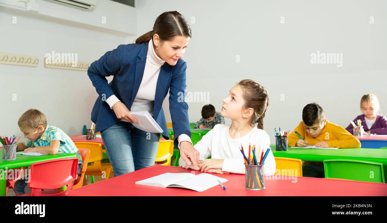 Teacher woman helping children during lesson Stock Photo - Alamy