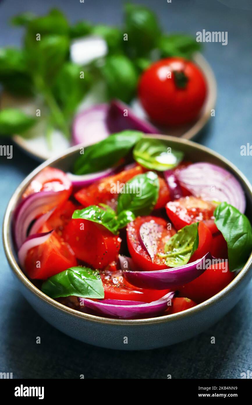 Bright healthy salad with tomatoes, basil and blue onions. Stock Photo