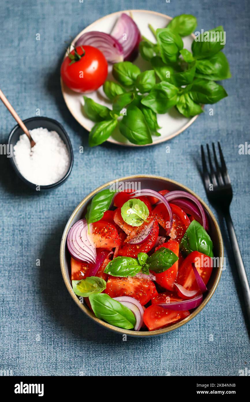 Bright healthy salad with tomatoes, basil and blue onions. Stock Photo