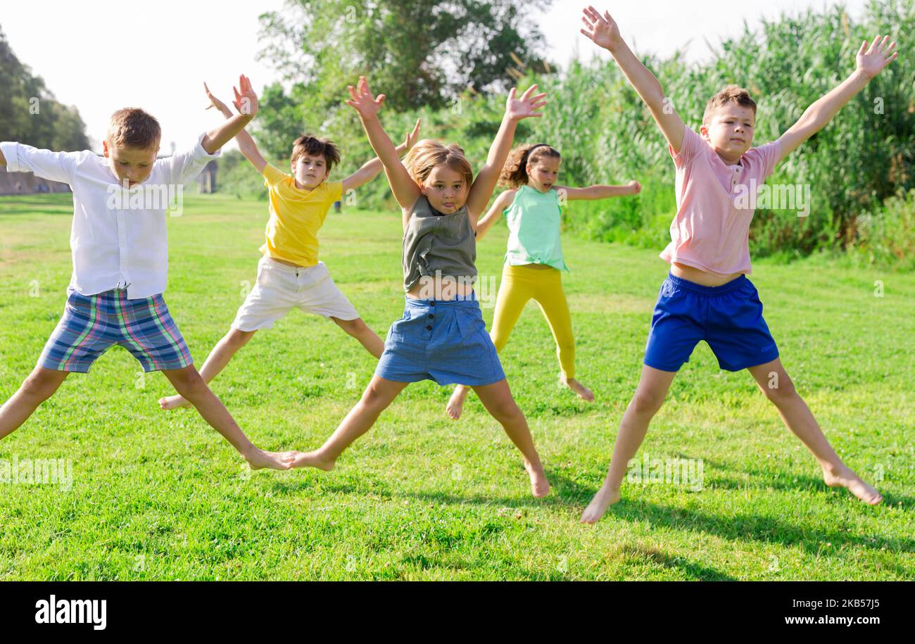 Group of five happy children jumping outdoors., Group of fi…