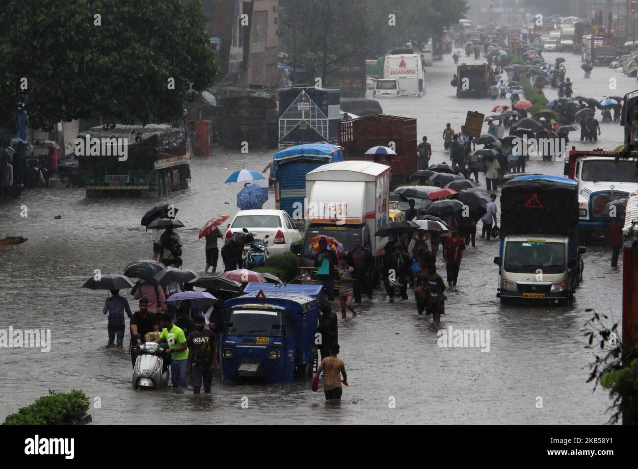 People wade through a flooded street during heavy rains in Mumbai ...