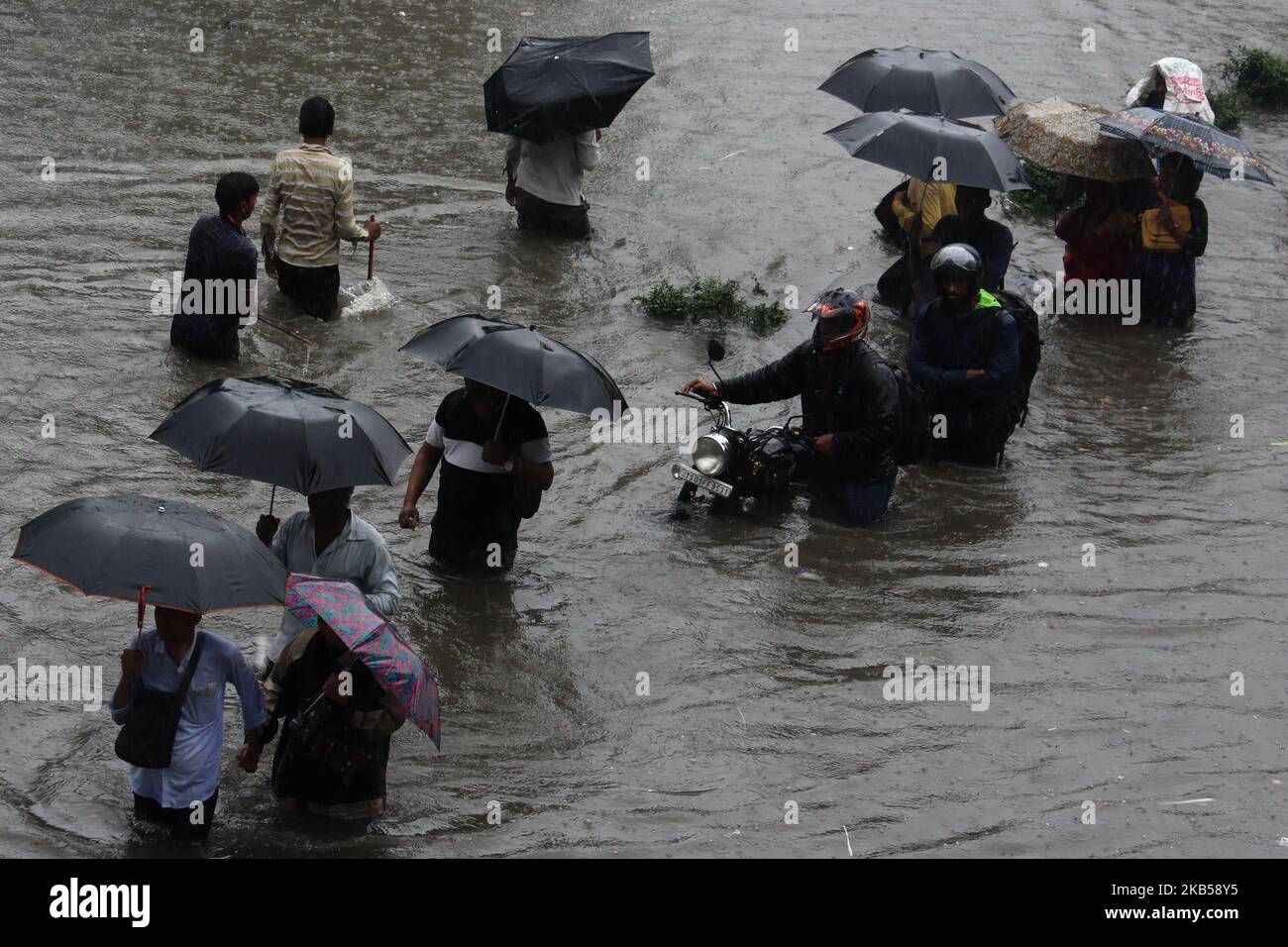People wade through a flooded street during heavy rains in Mumbai ...
