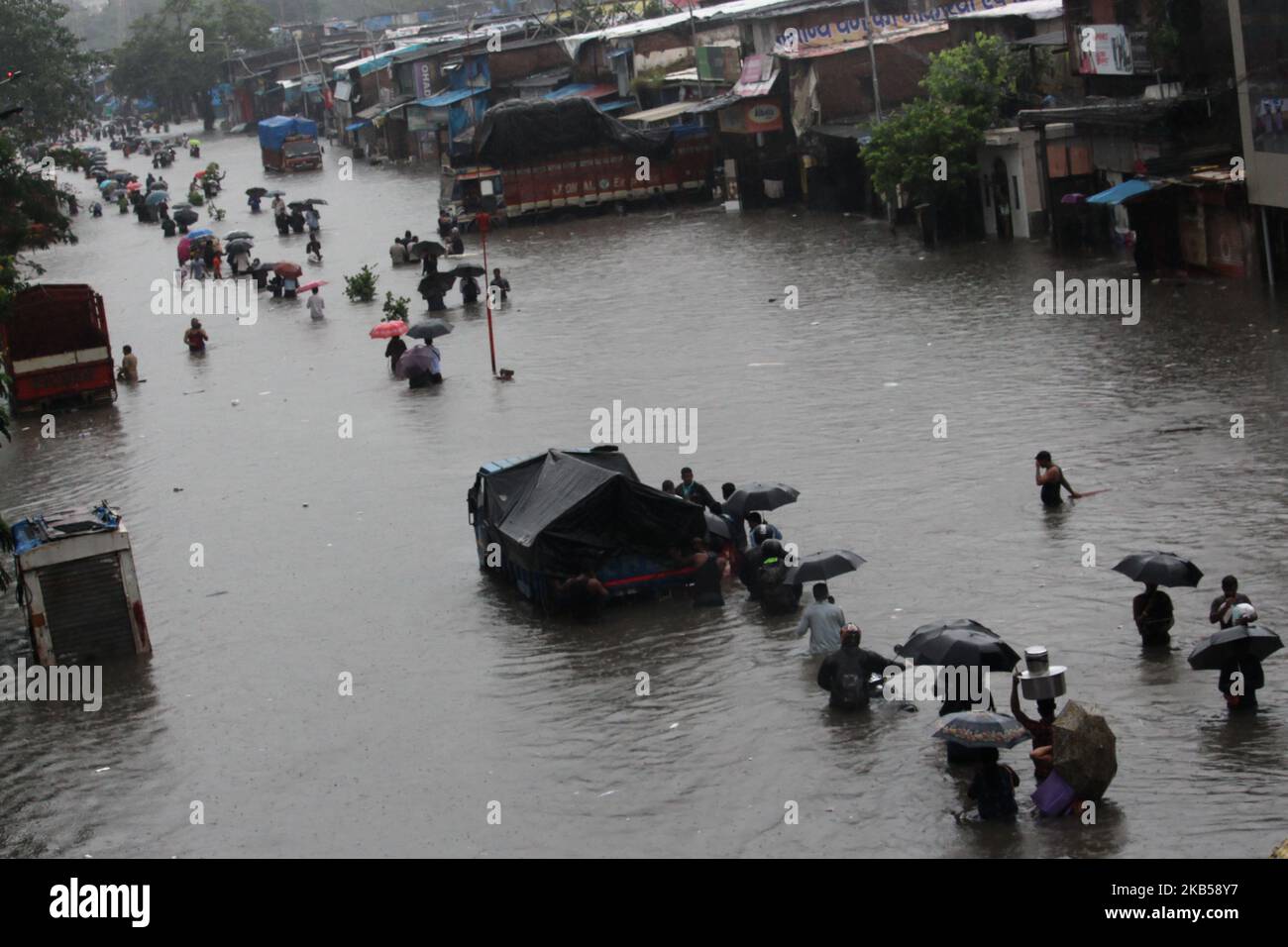 People wade through a flooded street during heavy rains in Mumbai ...