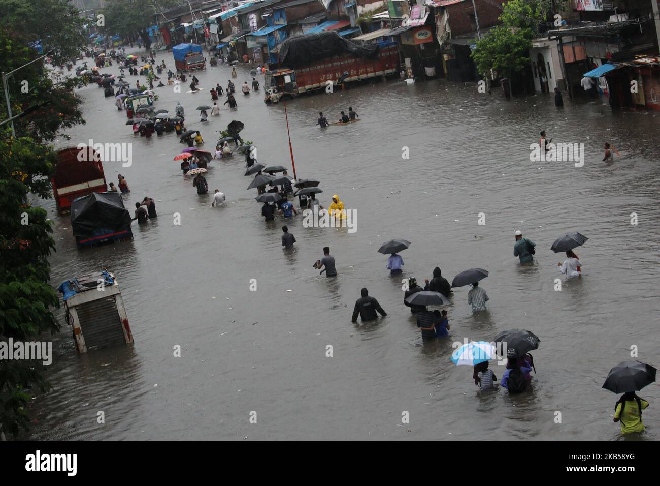 People wade through a flooded street during heavy rains in Mumbai ...