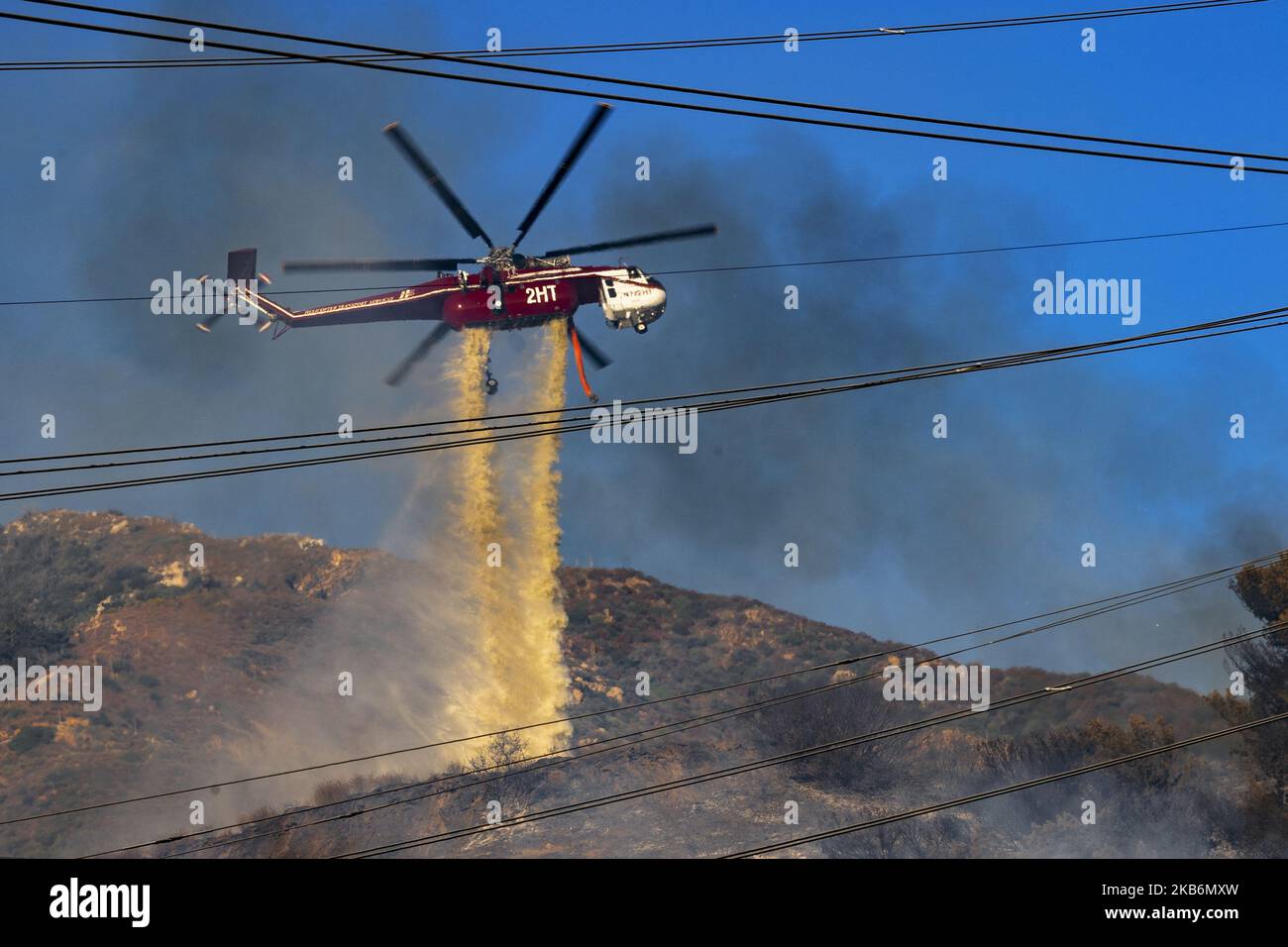 A firefighting helicopter makes a water drop on a wildfire in Altadena