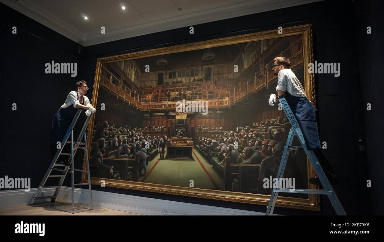 Gallery workers pose with the Banksy painting 'Devolved Parliament' at Sotheby's on September 27, 2019 in London, England. Photo call for Banksy's Devolved Parliament painting ahead of it being offered at auction by Sotheby's. The artwork showing the House of Commons full of chimpanzees is expected to fetch GBP1.5 to GBP2 million. (Photo by Giannis Alexopoulos/NurPhoto) Stock Photo