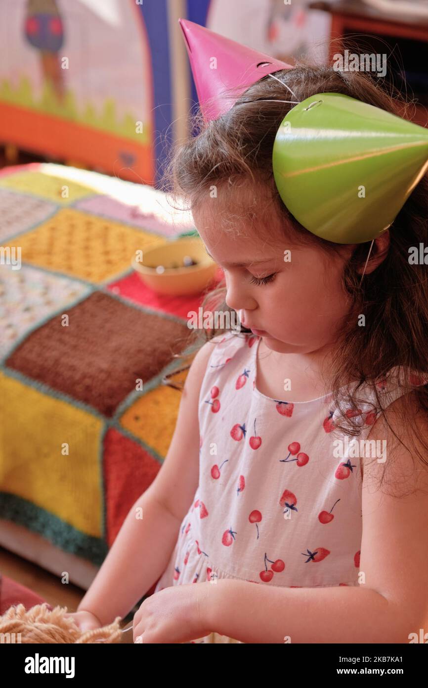 little girl in a party hat eating cake at her brother's first birthday