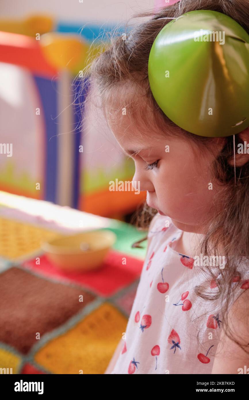little girl in a party hat eating cake at her brother's first birthday