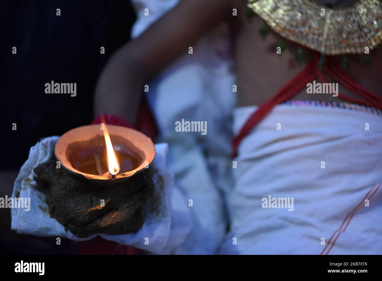 A Nepalese devotee hold oil lamps on his hands during the tenth day of