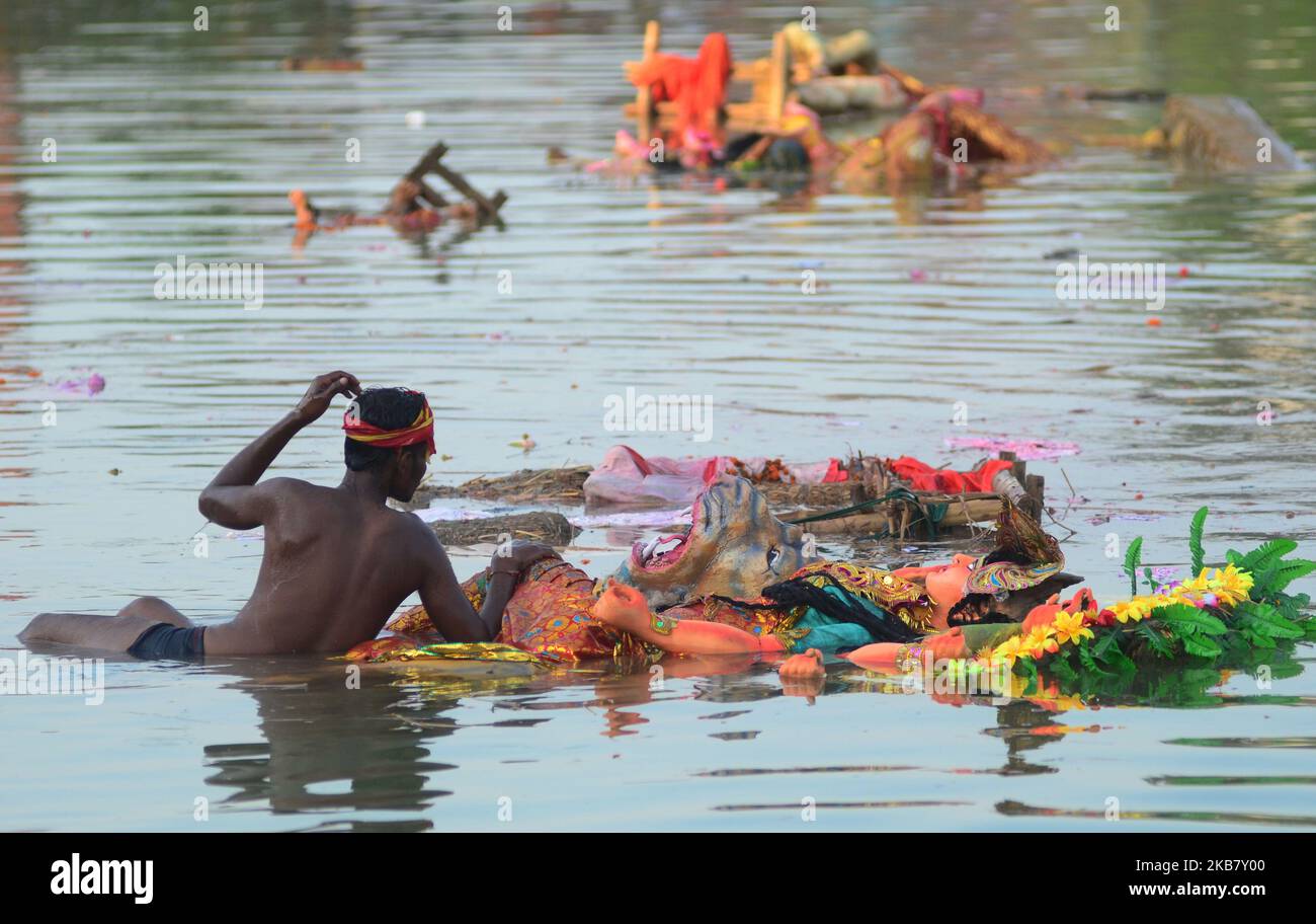 An indian man helps in immersion of idols of Goddess Durga in a temporary pond , in Allahabad on October 8,2019. The immersion of the idols marks the end of five day festival that commemorates the slaying of a demon king by lion riding ,ten armed Goddess Durga,marking the triumph of Good over evil.(Photo by Ritesh Shukla ) (Photo by Ritesh Shukla/NurPhoto) Stock Photo
