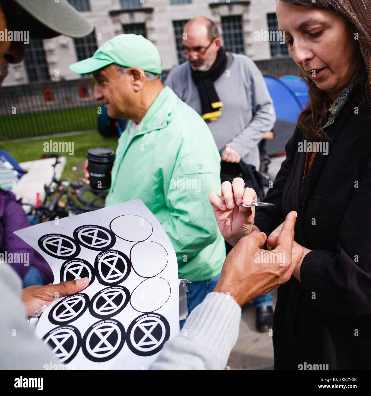 A members of climate change activist group Extinction Rebellion (XR) hands out stickers on Whitehall on the second day of the group's 'International Rebellion' in London, England, on October 8, 2019. By early Tuesday evening the Metropolitan Police were reporting that a total of 531 arrests had been made over the two days of protests in the city so far, with police officers working to clear people and tents from many of the sites taken over by activists yesterday. Similar blockades by Extinction Rebellion in April, at sites including Oxford Circus and Waterloo Bridge, saw more than 1,000 arres Stock Photo