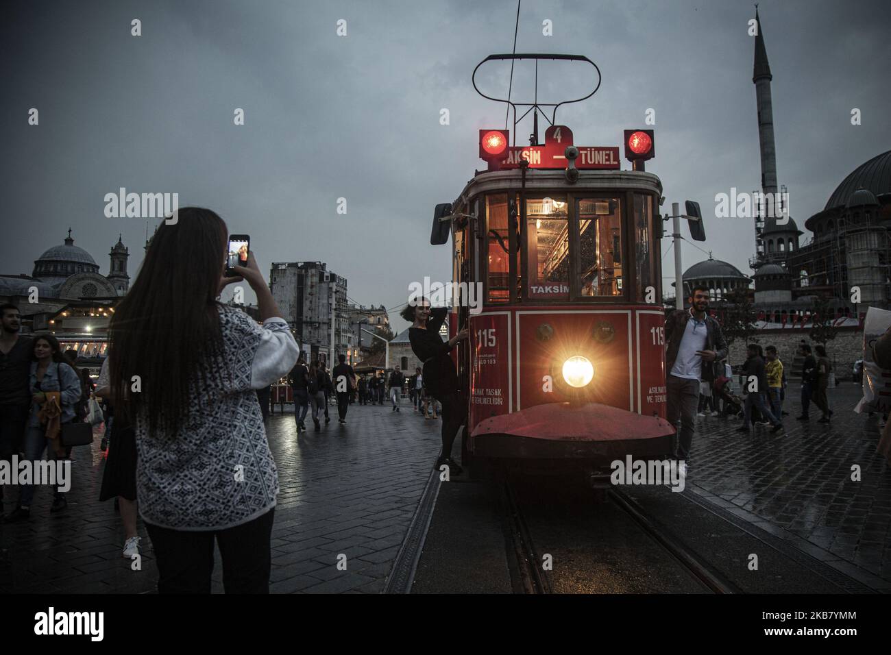 Tourists take souvenir photos with an old-fashioned red tram in Taksim Square and Istiklal Street on a rainy and cold day.The Taksim area of Istanbul is famous for its shopping, restaurants, cafes, bars and dance clubs 08 Oct 2019, Istanbul, Turkey Istanbul(Photo by Momen Faiz/NurPhoto) Stock Photo