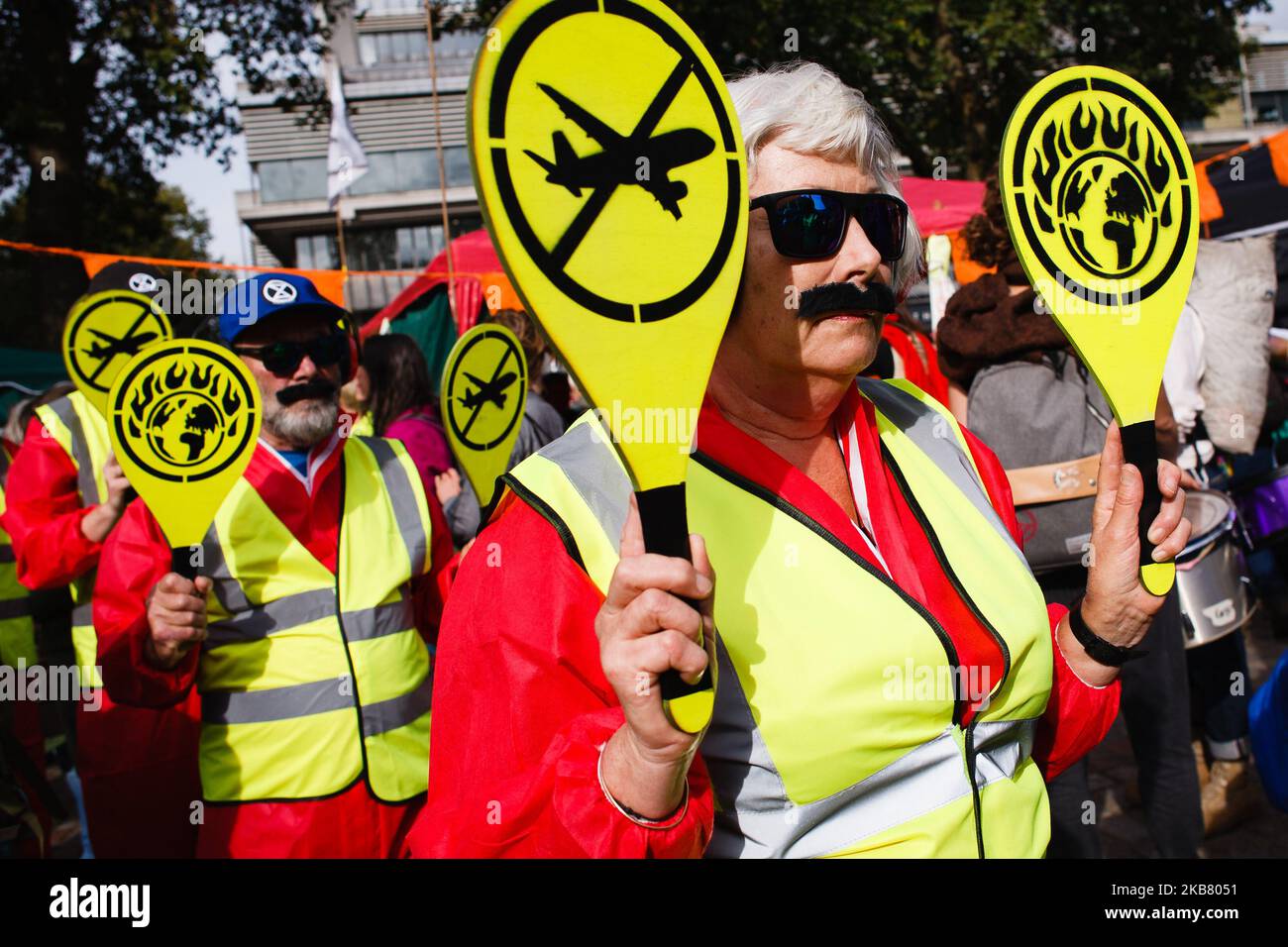 Members of climate change activist movement Extinction Rebellion (XR) dressed as air traffic controllers, with paddles bearing anti-aviation logos, demonstrate on Victoria Street on the third day of the group's 'International Rebellion' in London, England, on October 9, 2019. Police officers today continued to clear demonstrators and tents from sites across Westminster, with activists having been warned yesterday that they must move to a designated protest area around Nelson's Column in Trafalgar Square or face arrest. Similar blockades by Extinction Rebellion in April, at sites including Oxfo Stock Photo