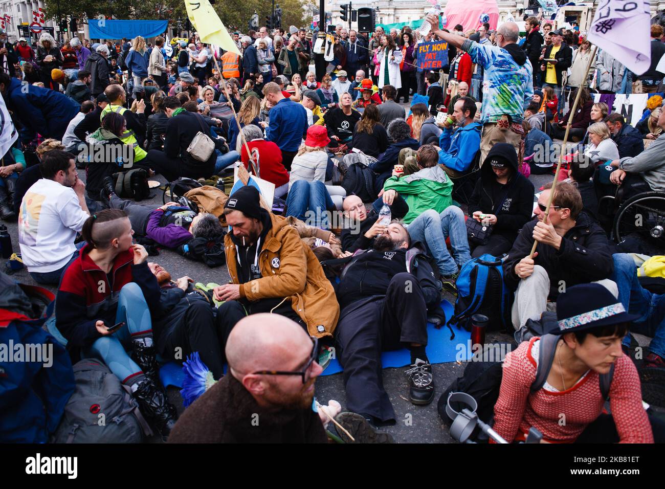 Members of climate change activist movement Extinction Rebellion (XR) listen to a talk on climate science at Trafalgar Square on the fourth day of the group's two-week 'International Rebellion' in London, England, on October 10, 2019. By lunchtime Thursday police had all but contained the demonstrations in Trafalgar Square and the roadways around it, where sizeable numbers of XR followers remained. A hearse carrying a coffin for 'Our Future', which had been parked at the Whitehall exit from the square since Monday, was removed early afternoon. (Photo by David Cliff/NurPhoto) Stock Photo