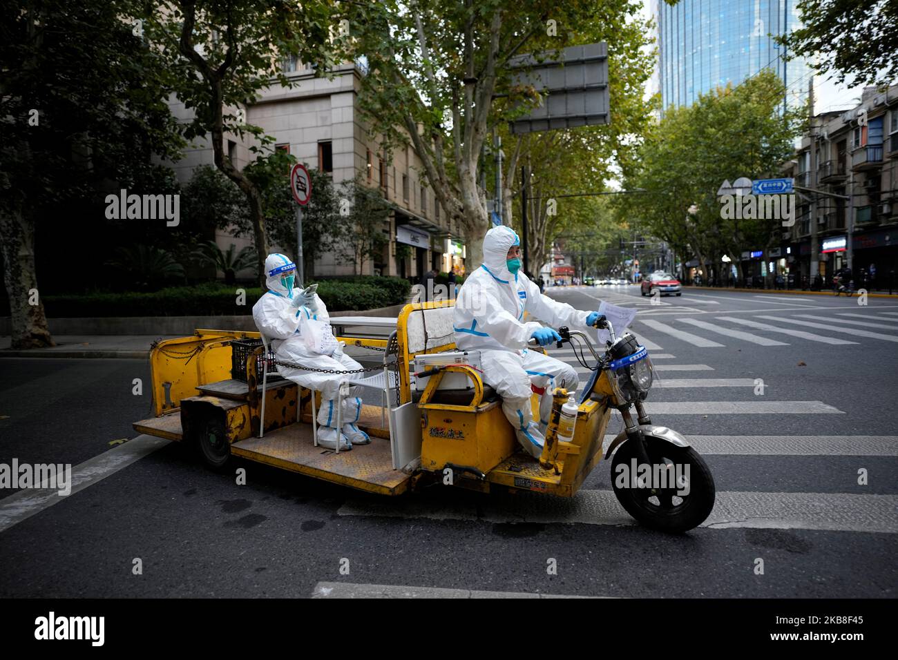 Medical workers in protective suits ride an electric tricycle on a street, following the coronavirus disease (COVID-19) outbreak in Shanghai, China, November 3, 2022. REUTERS/Aly Song Stock Photo