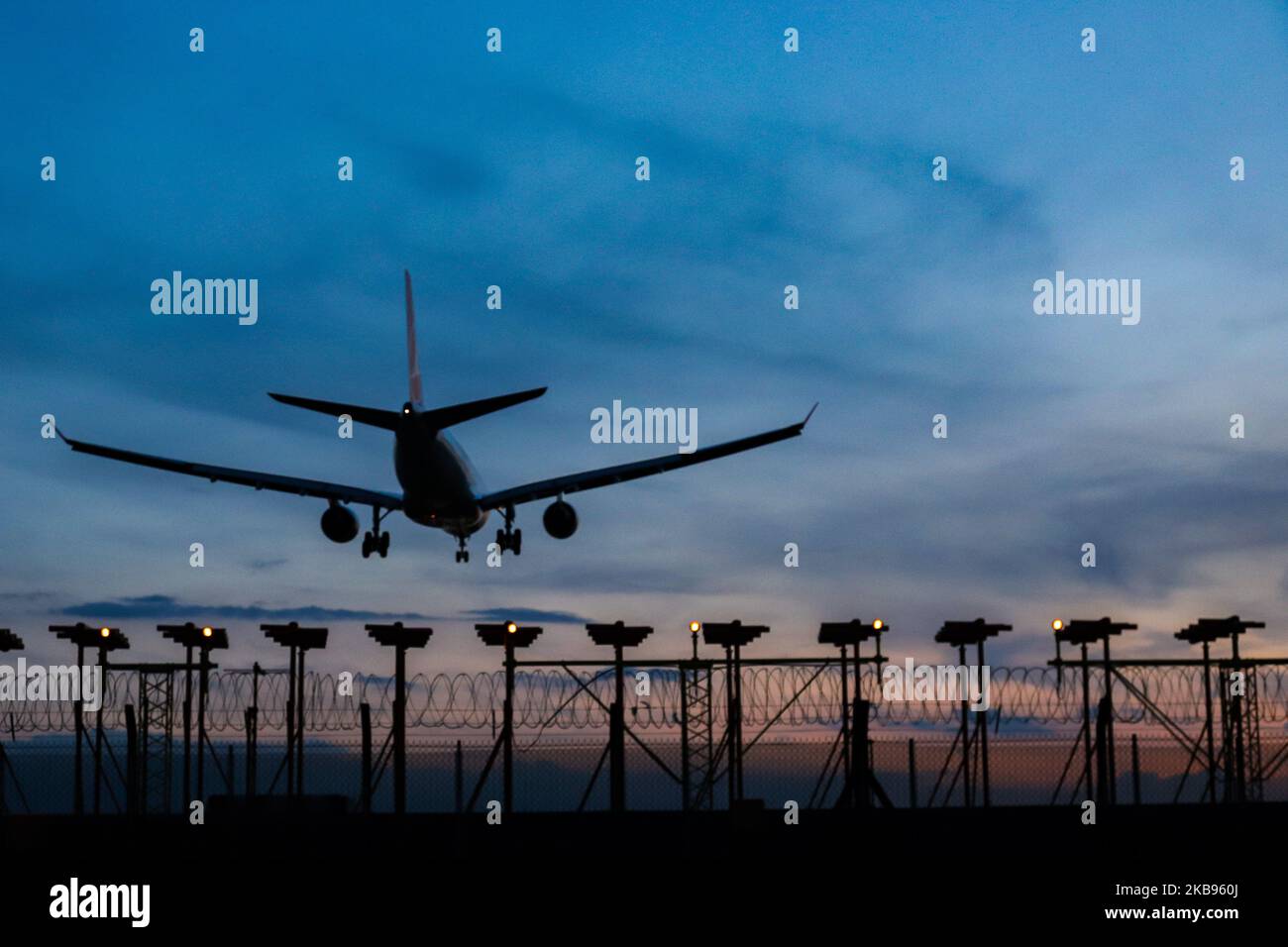 Airplane silhouettes while on final approach landing, during the sunset ...