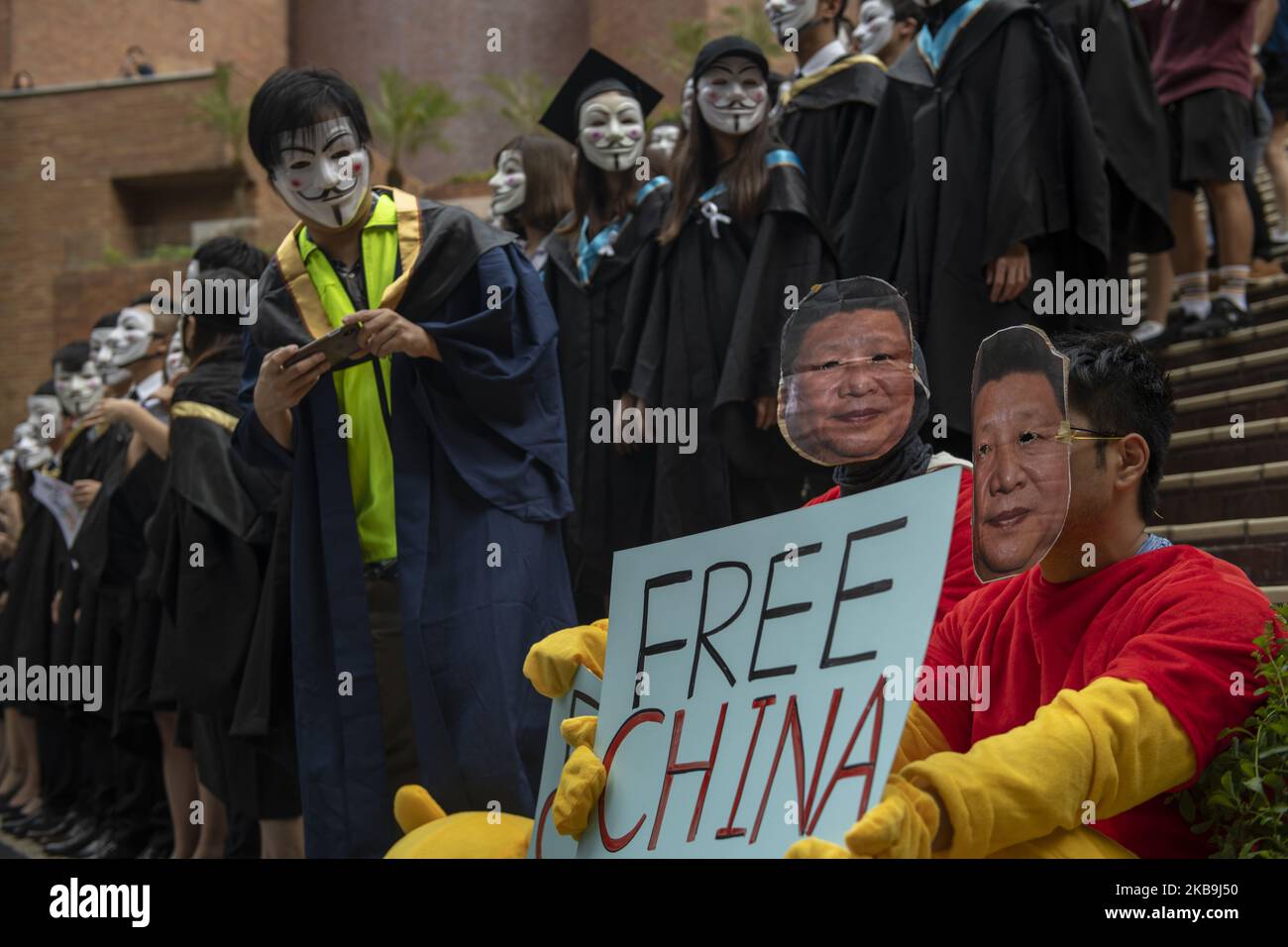 A Student wearing an Academic Dress and a Guy Fawkes Mask is seen taking a photo of a protester wearing a Xi Jinping mask in Polytechnic University in Hong Kong, China, October 30, 2019, (Photo by Vernon Yuen/NurPhoto) Stock Photo