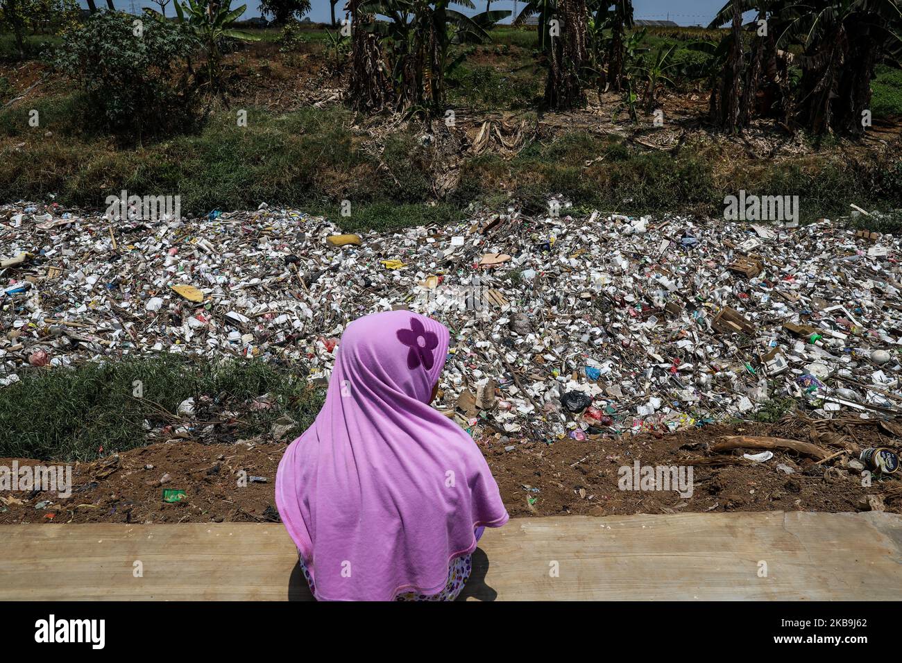 Java River Pollution A girl sits in front of a river covered by garbage in Bekasi, West Java ...