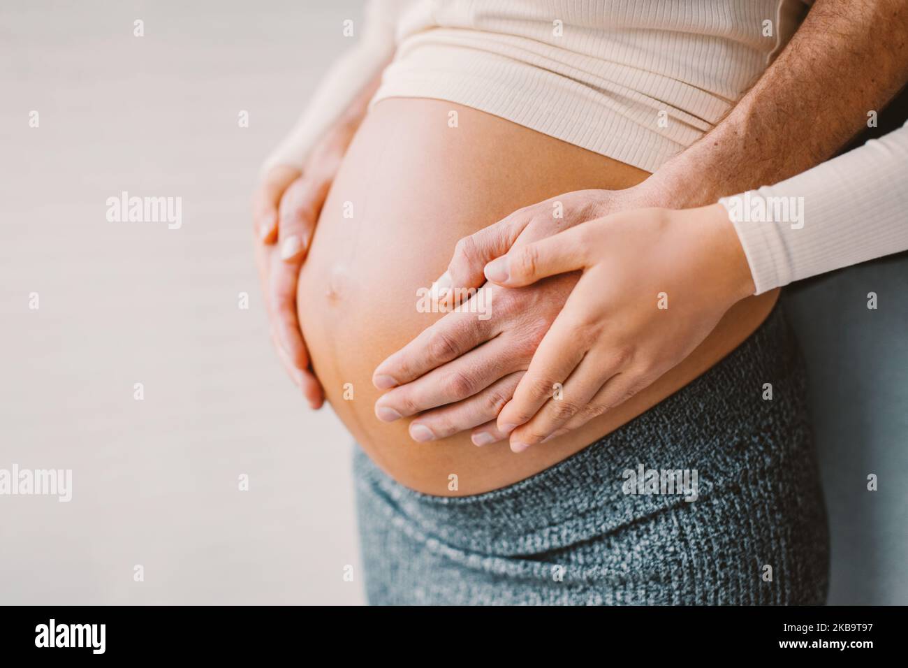 Pregnancy photo man and woman holding pregnant bump expecting baby. Happy family hands on stomach closeup. Couple in love. Stock Photo